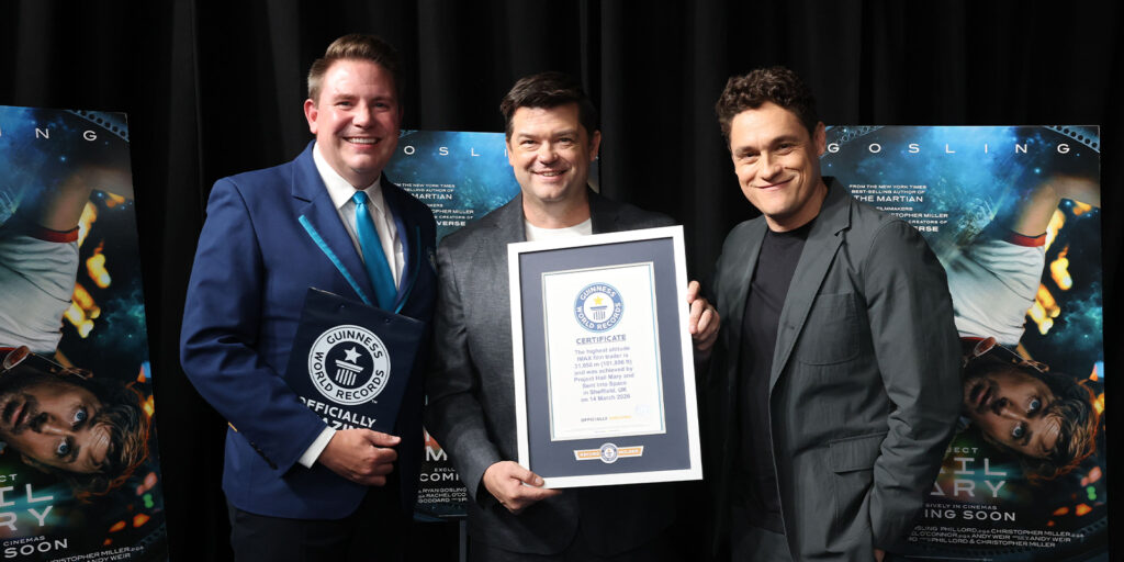 Three people posing together with a Guinness World Record certificate
