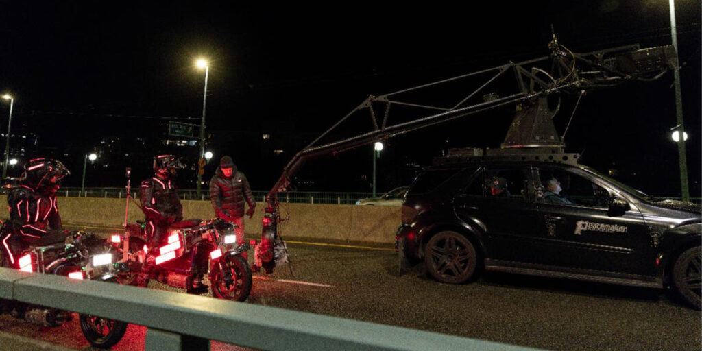 A group of motorbikes being filmed by a camera on a crane arm