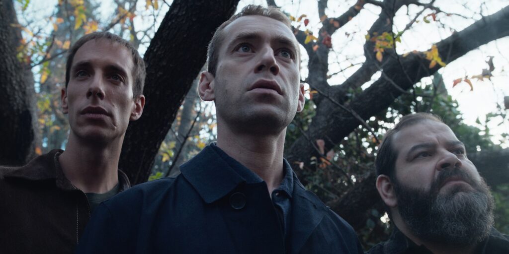 Three men stood in the woods looking concerned 