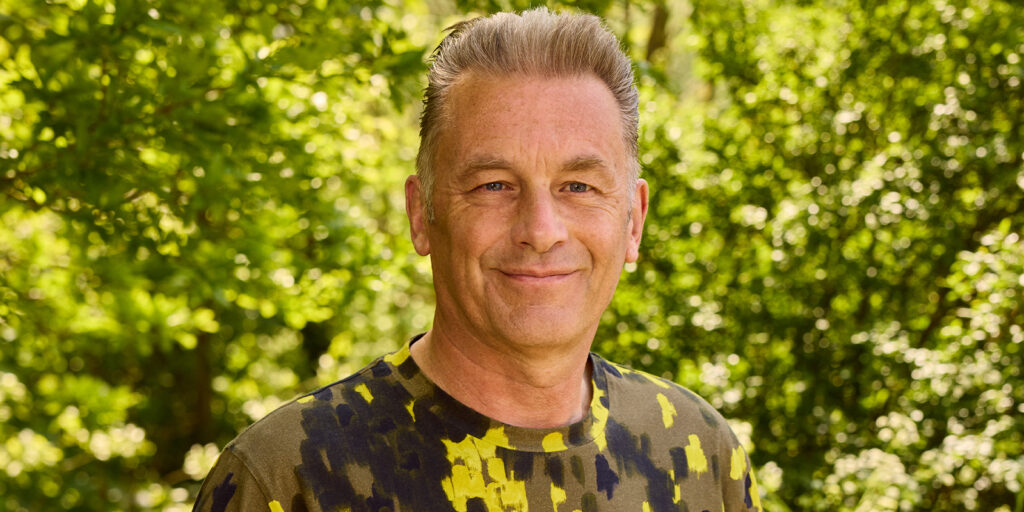 Chris Packham in a camo shirt smiling into camera