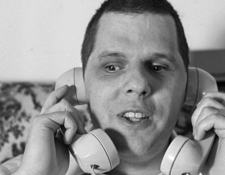 A man holding a telephone to each ear