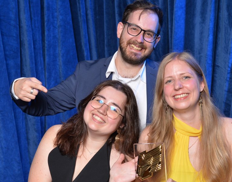Three people celebrating with an award