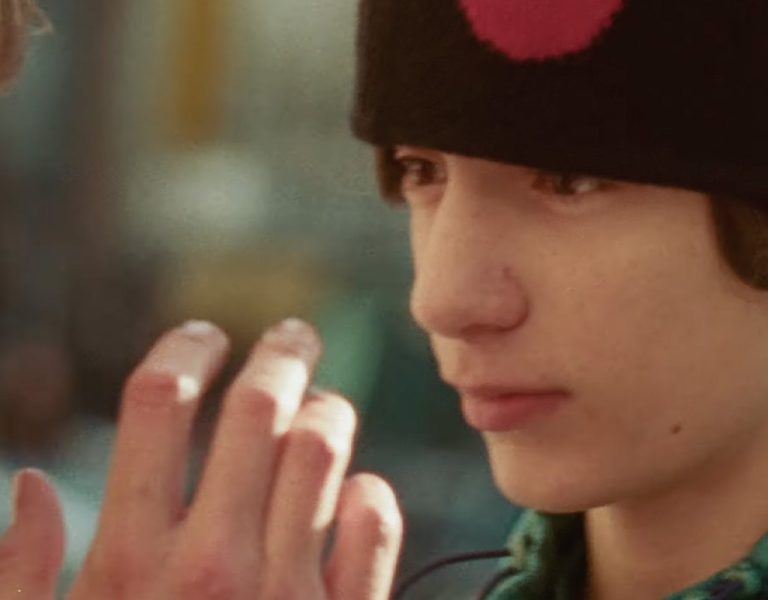 A boy in a hat being talked to by a man