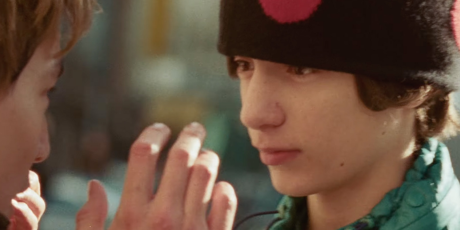 A boy in a hat being talked to by a man