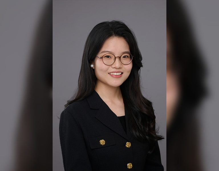 A woman smiling against a grey background