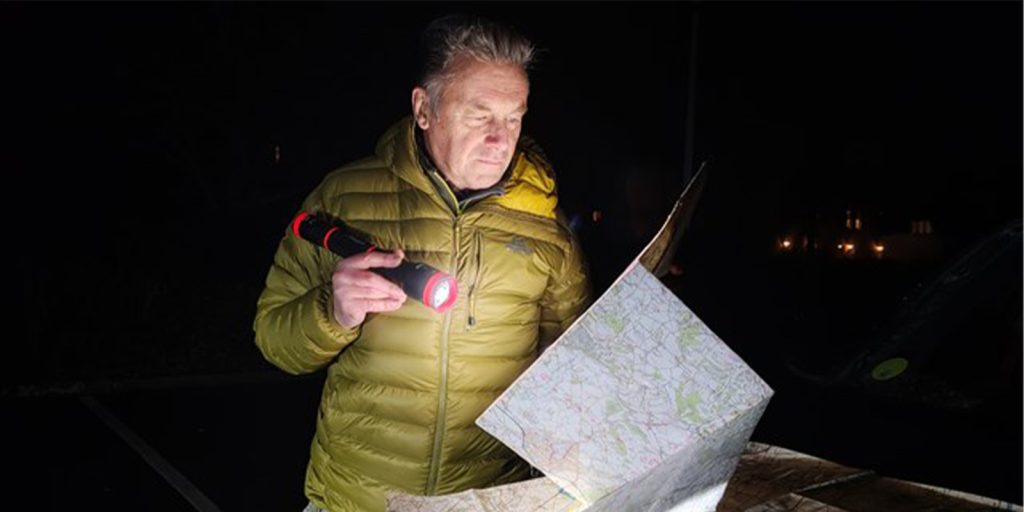 Chris Packham looking at a map in the dark