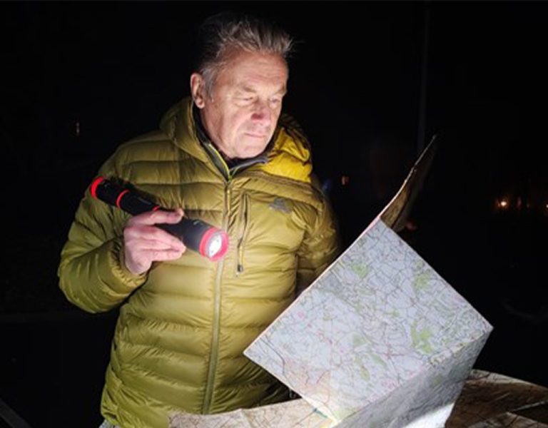 Chris Packham looking at a map in the dark