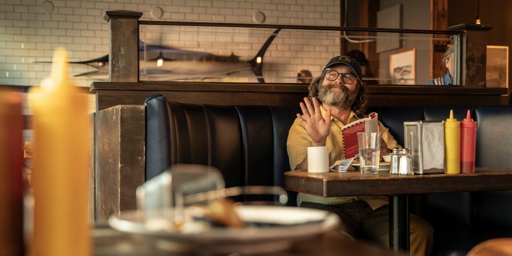 A man sat in a diner waving