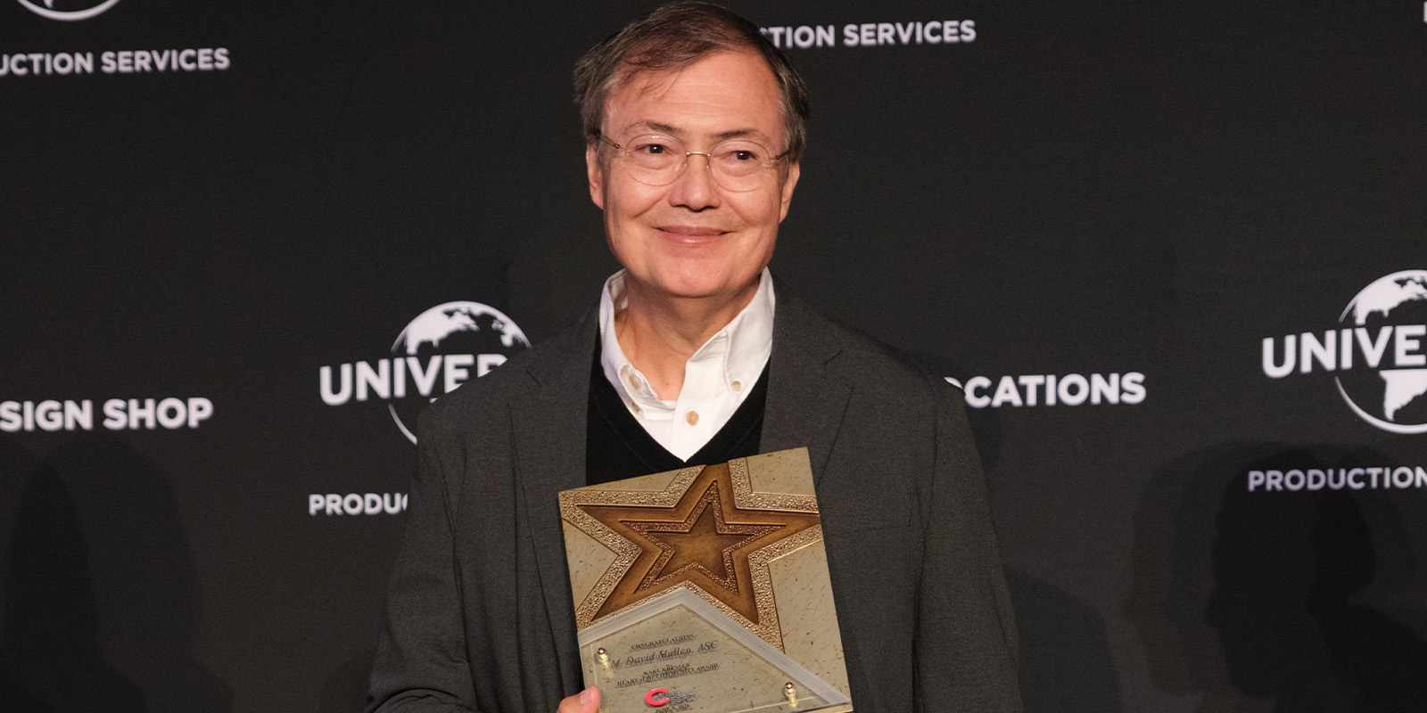 M David Mullen holding an award and smiling