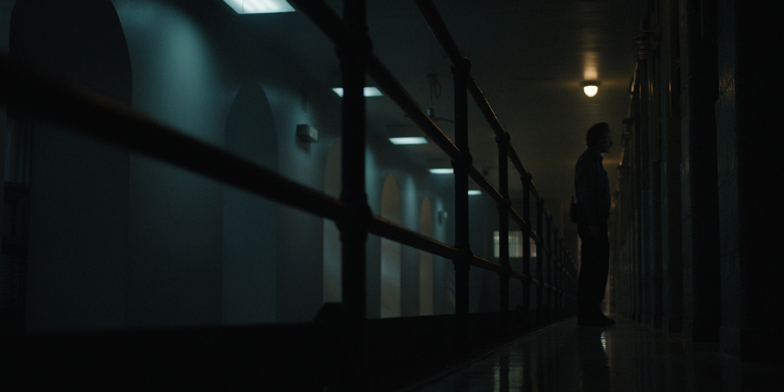 A man in a dimly lit prison corridor