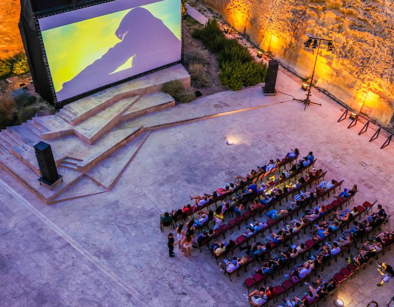 People gathered watching a screen in a historic location