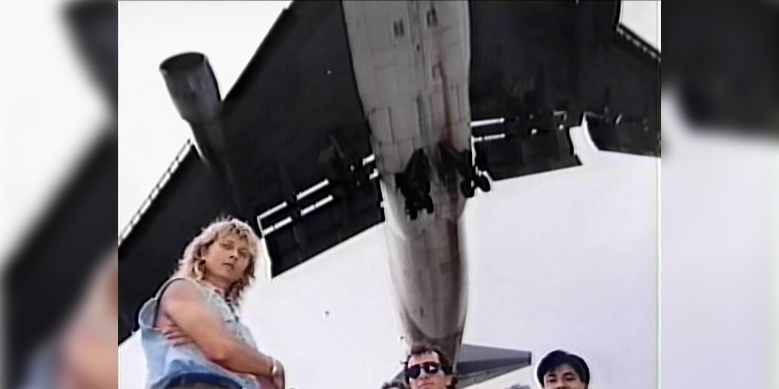 Men posing underneath a plane