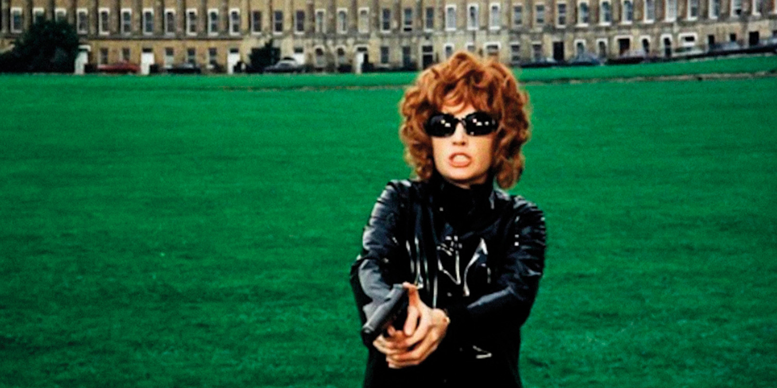 A woman in a leather jacket holding a pistol