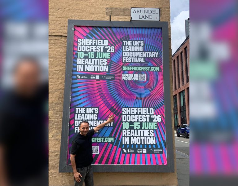 A man pointing at a Sheffield DocFest poster