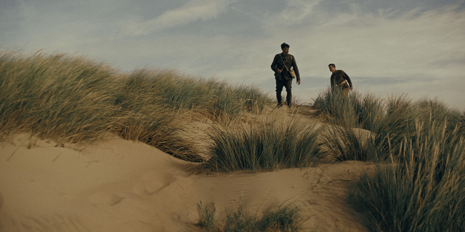 Two soldiers walking on sand dunes