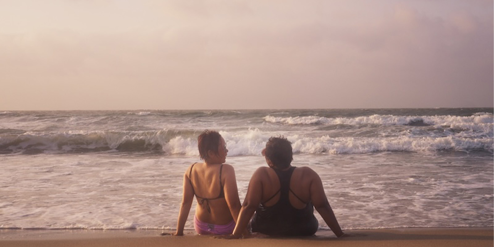 Two people sat by the sea