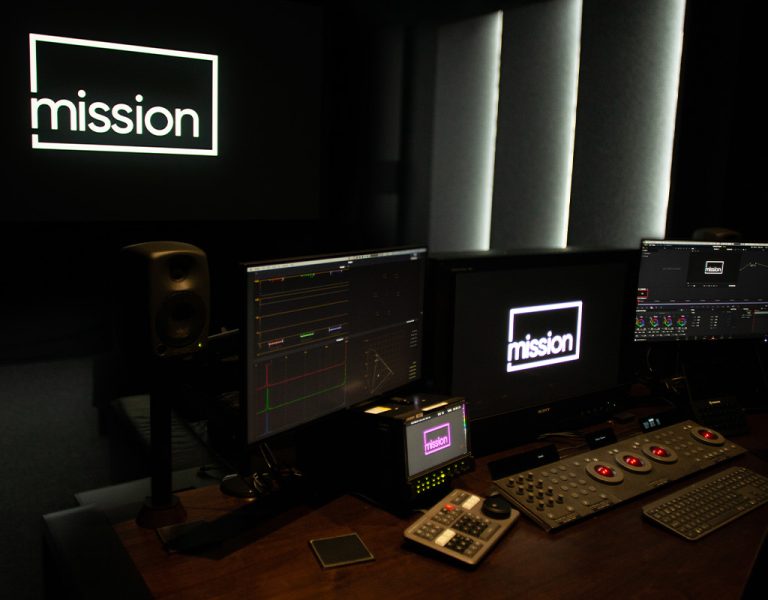 A computer setup with the Mission logo in the background