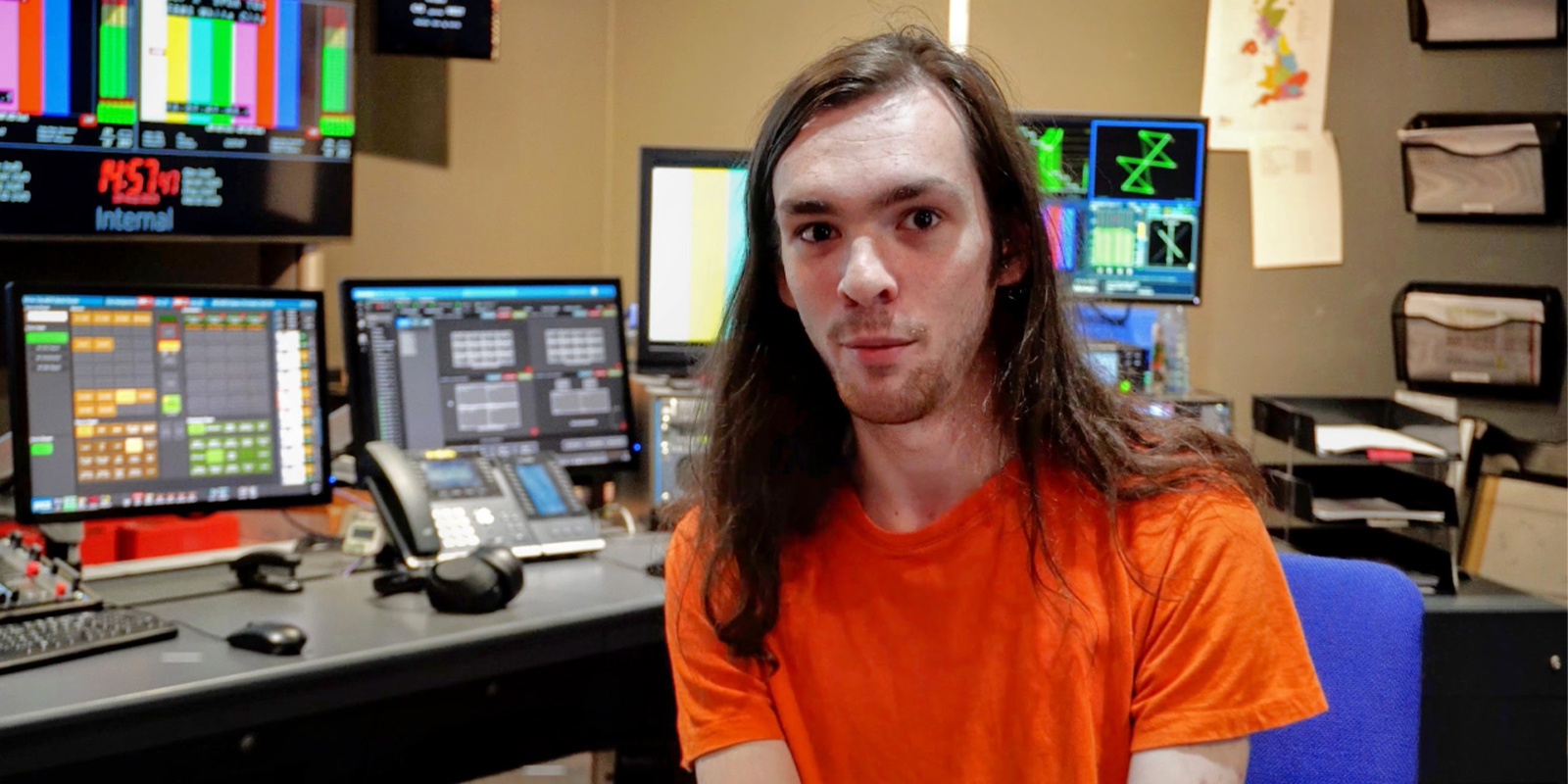 A man sat in an orange shirt 