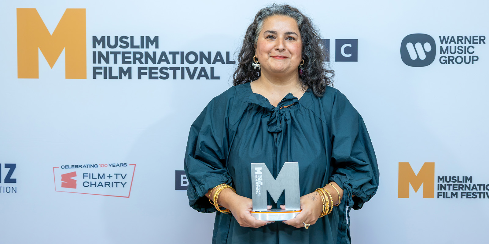Shaheen Baig holding an M-shaped trophy