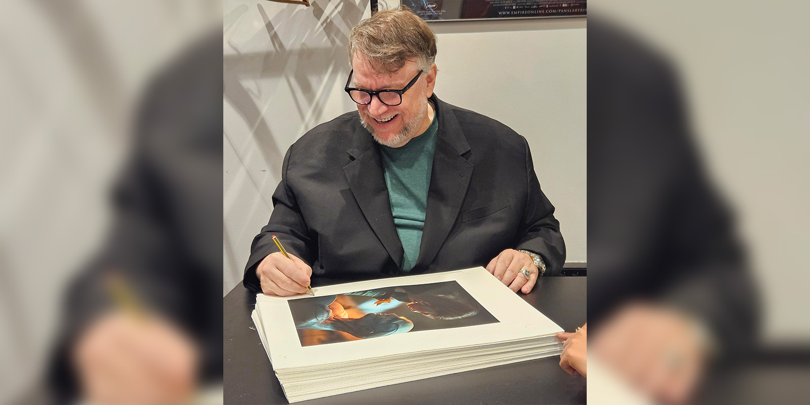 Guillermo del Toro smiling and signing photographs