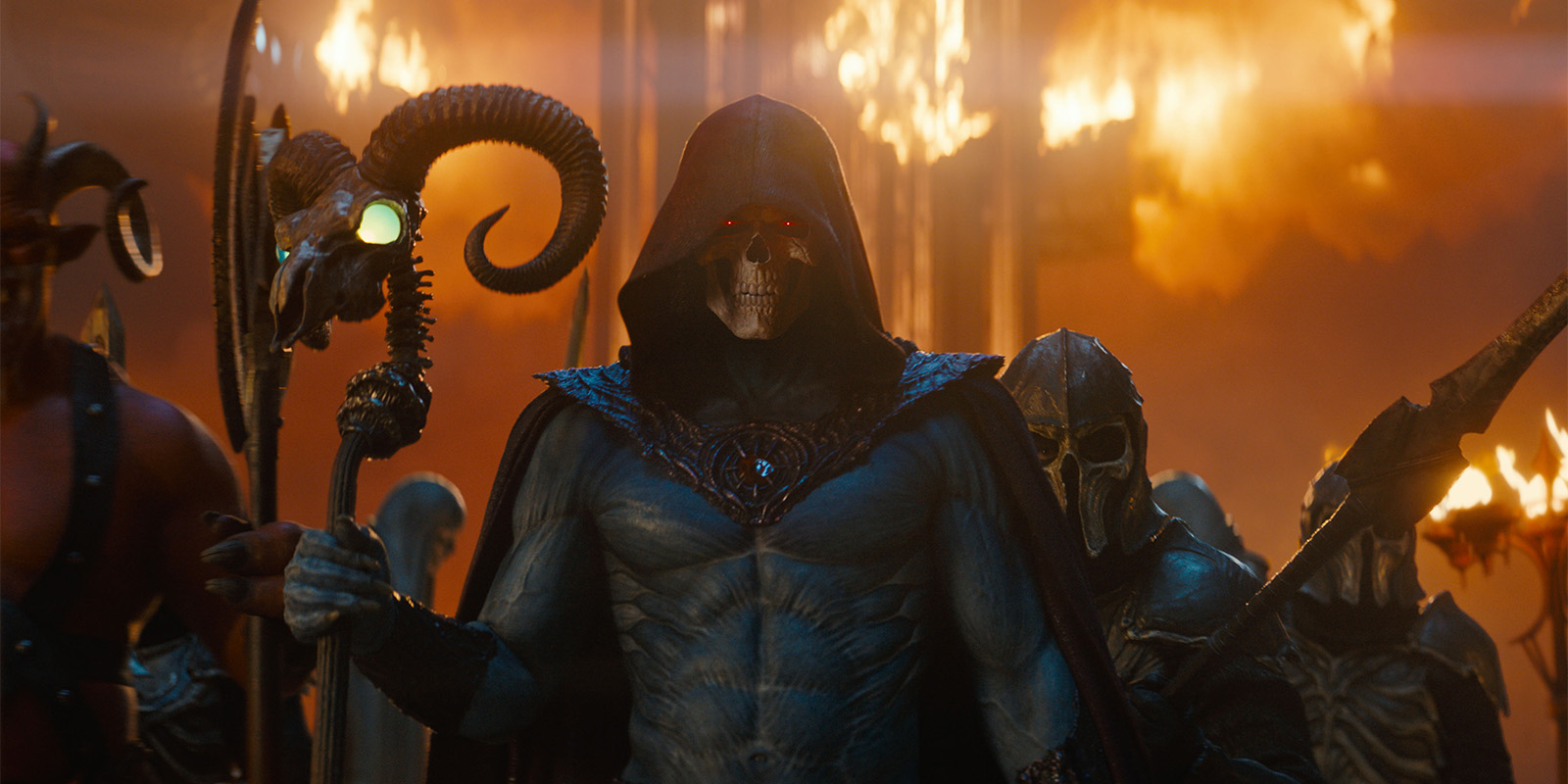 A hooded skeletal figure with glowing red eyes and blue skin holds a staff, standing in front of armoured figures and flames in the background. The scene appears intense and dramatic.